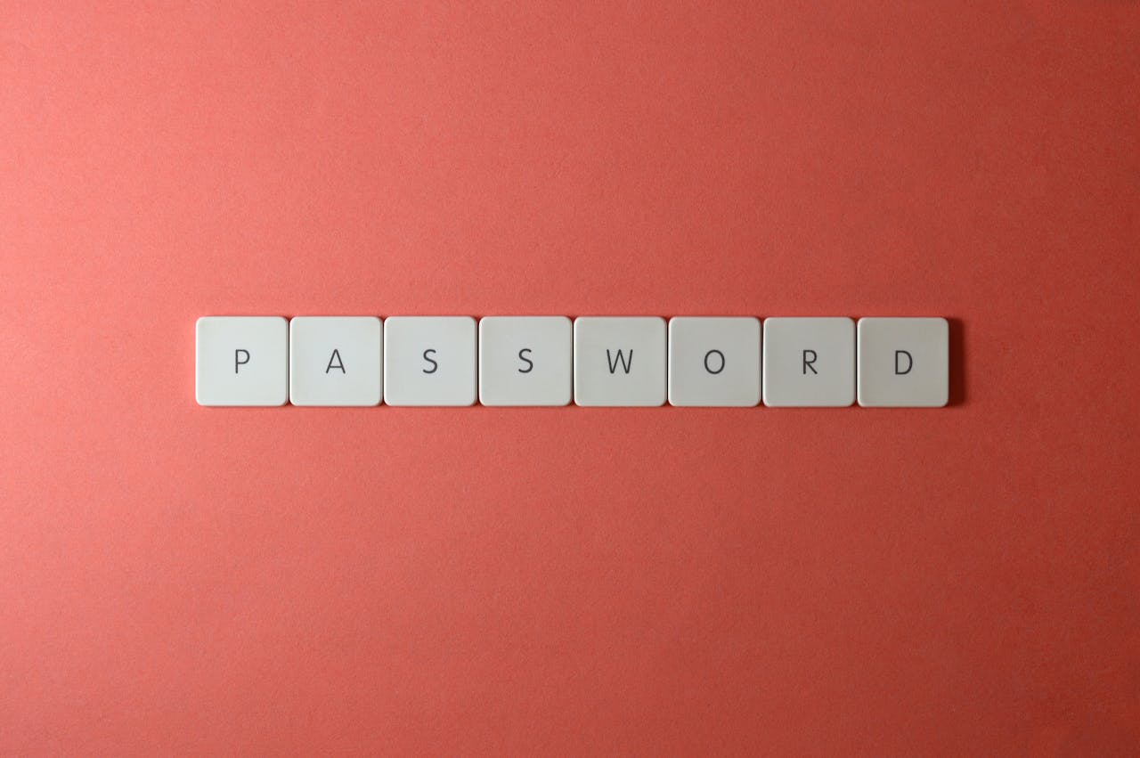 Focus on password security with white keyboard tiles spelling 'PASSWORD' on a coral background.